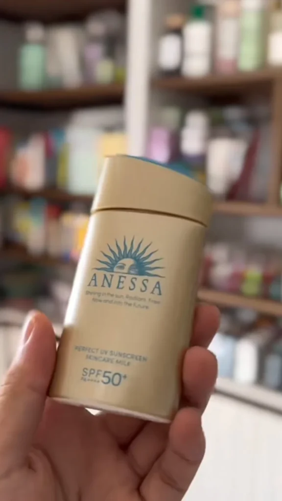 Close-up of Anessa Perfect UV Sunscreen Skincare Milk SPF50+ bottle held in hand